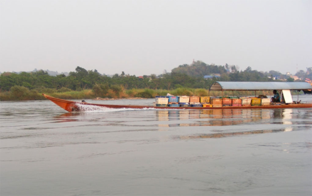 Below: The Mekong River is used for transportation — crops and food travel up and down the river by longboat. Some of these boats have large inboard motors that run on propane; others have outboard motors with spinning propellers at the end of 10-foot long shafts. The river bursts with the noise of boat traffic, fisherman and even local students hollering out commands as they row crew. 