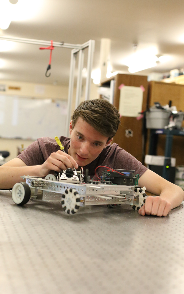 A Dawson School student works on the construction of a robot.